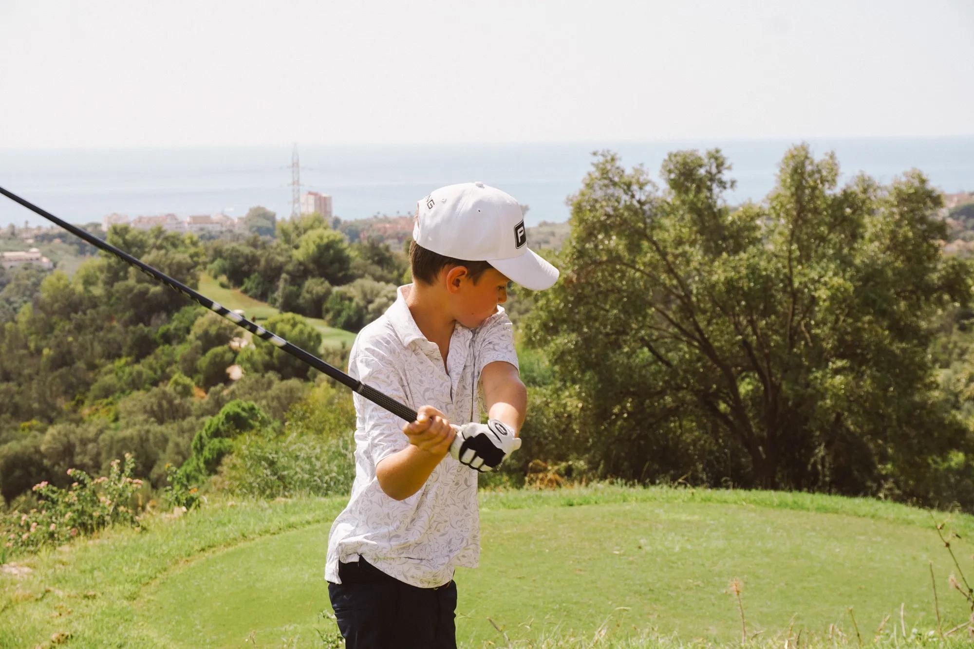Junior golf player teeing off