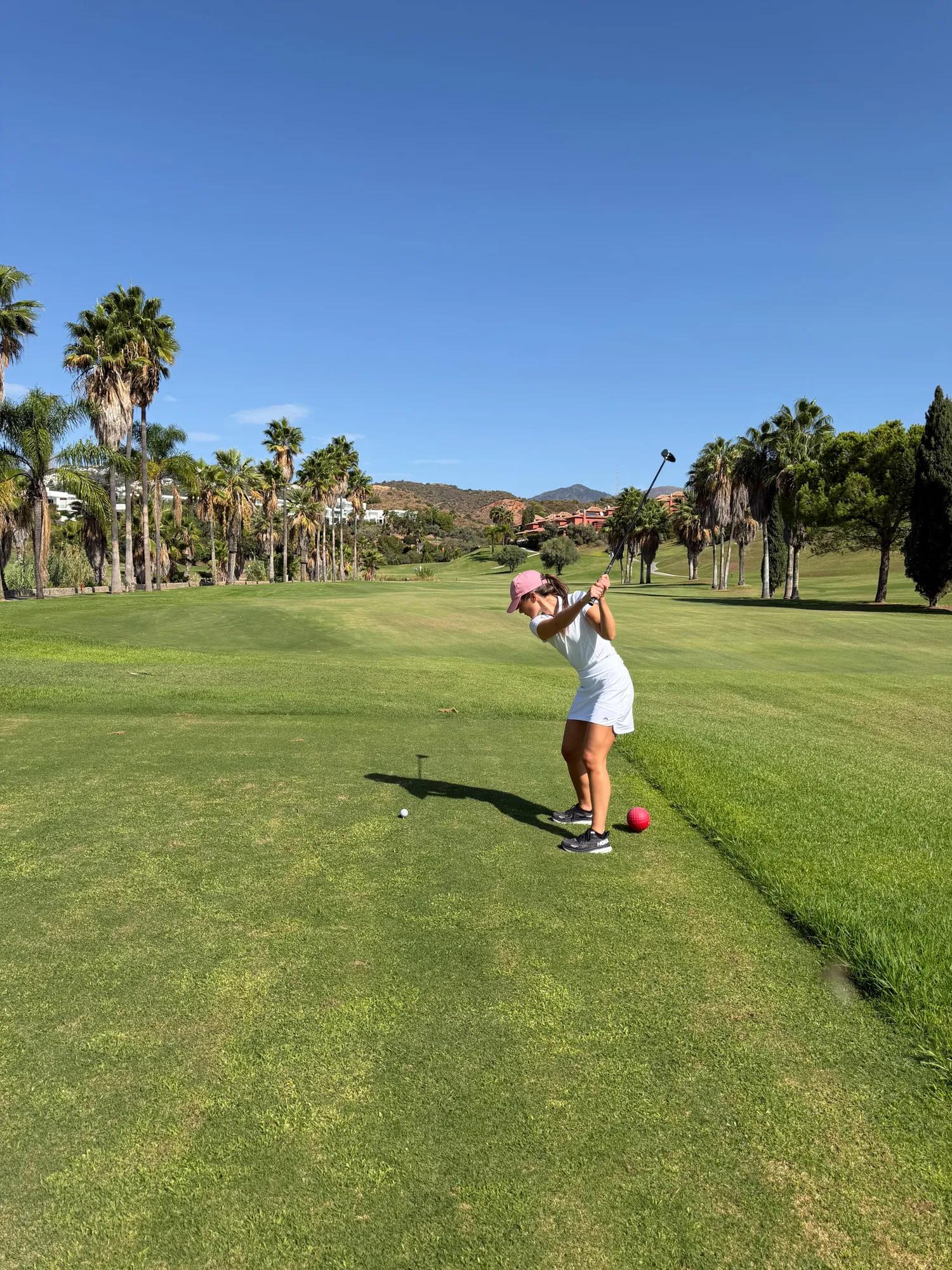 female golf player with pink cap and white outfit
