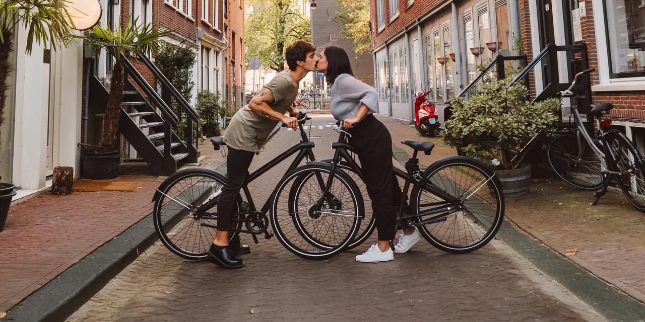 et par kysser mens de st&aring;r med hver sin sykkel i amsterdam
